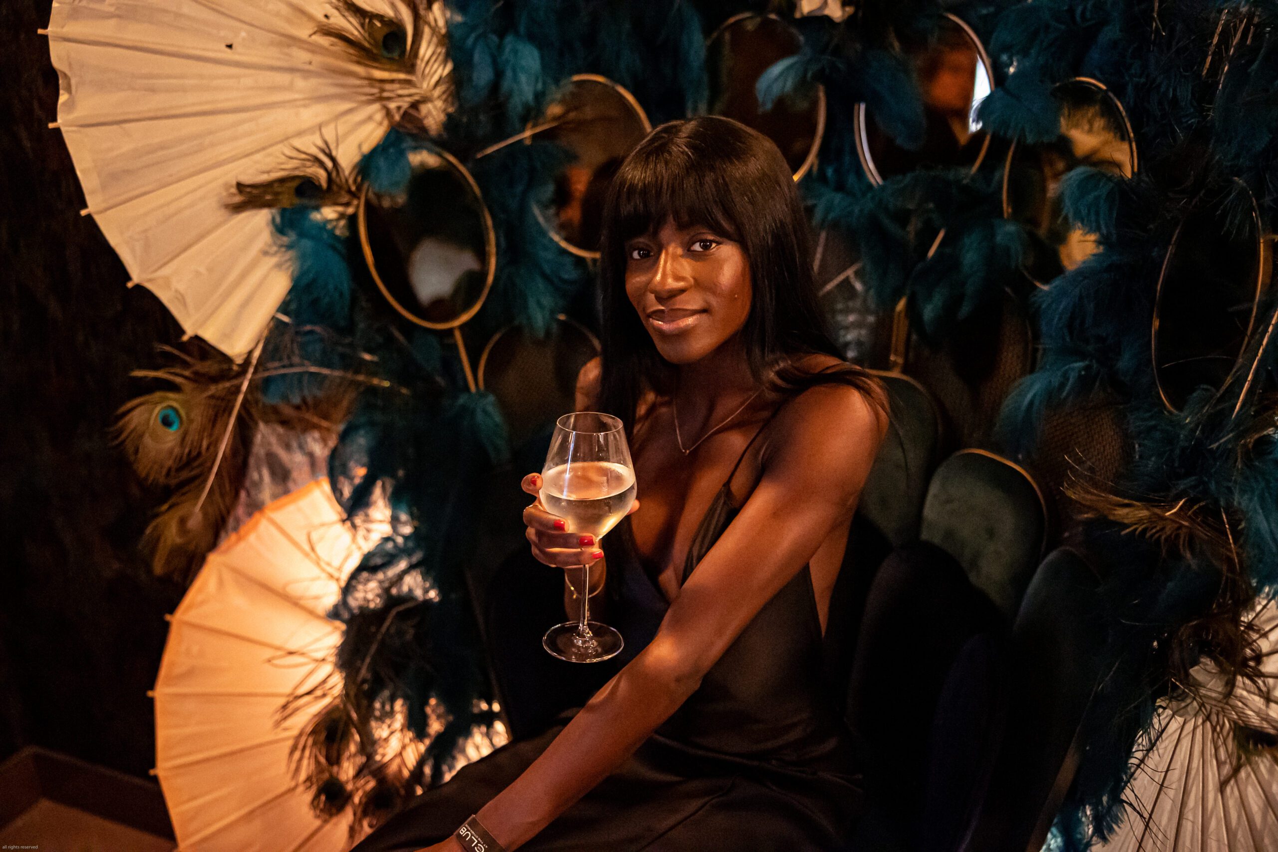 A lady poses for London event photographer natalie martinez on a throne of peacock feathers
