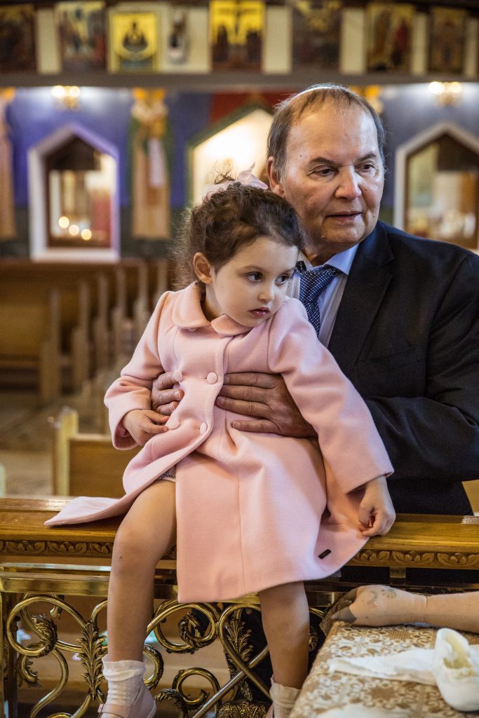 A grandfather and granddaughter at a Greek christening photographer, twelve apostles church, brookmans Park, Hertfordshire