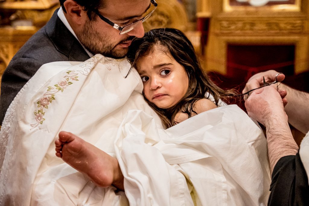 little girl at greek christening, a lock of her hair is being cut