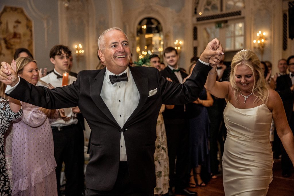 A groom smiles and dances at wedding at The savoy hotel in London.