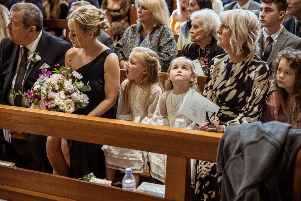 flower girls sit patiently at hertford church wedding