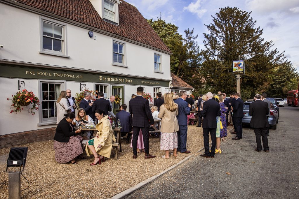wedding guests outside The Sword Inn Hand pub in Hertfordshire