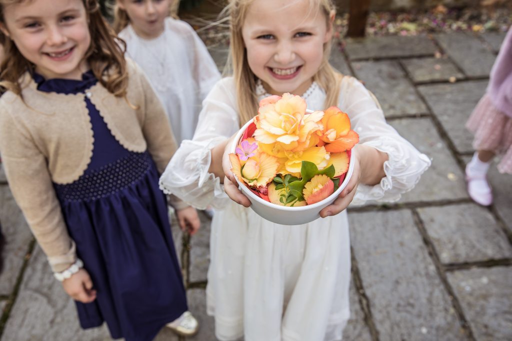A flower girl holds up a bowl of flowers