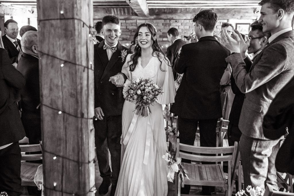 the bride and groom walk through their guests at the Barley Townhouse in Royston