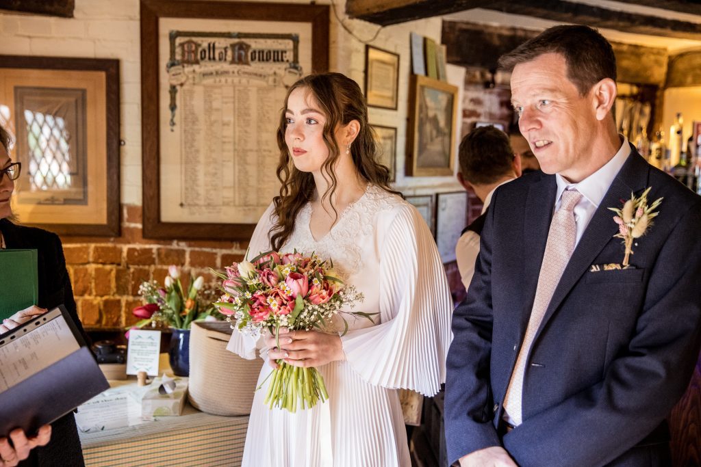 a bride and her father wait outside to go into the ceremony at The Barley Townhouse in Royston