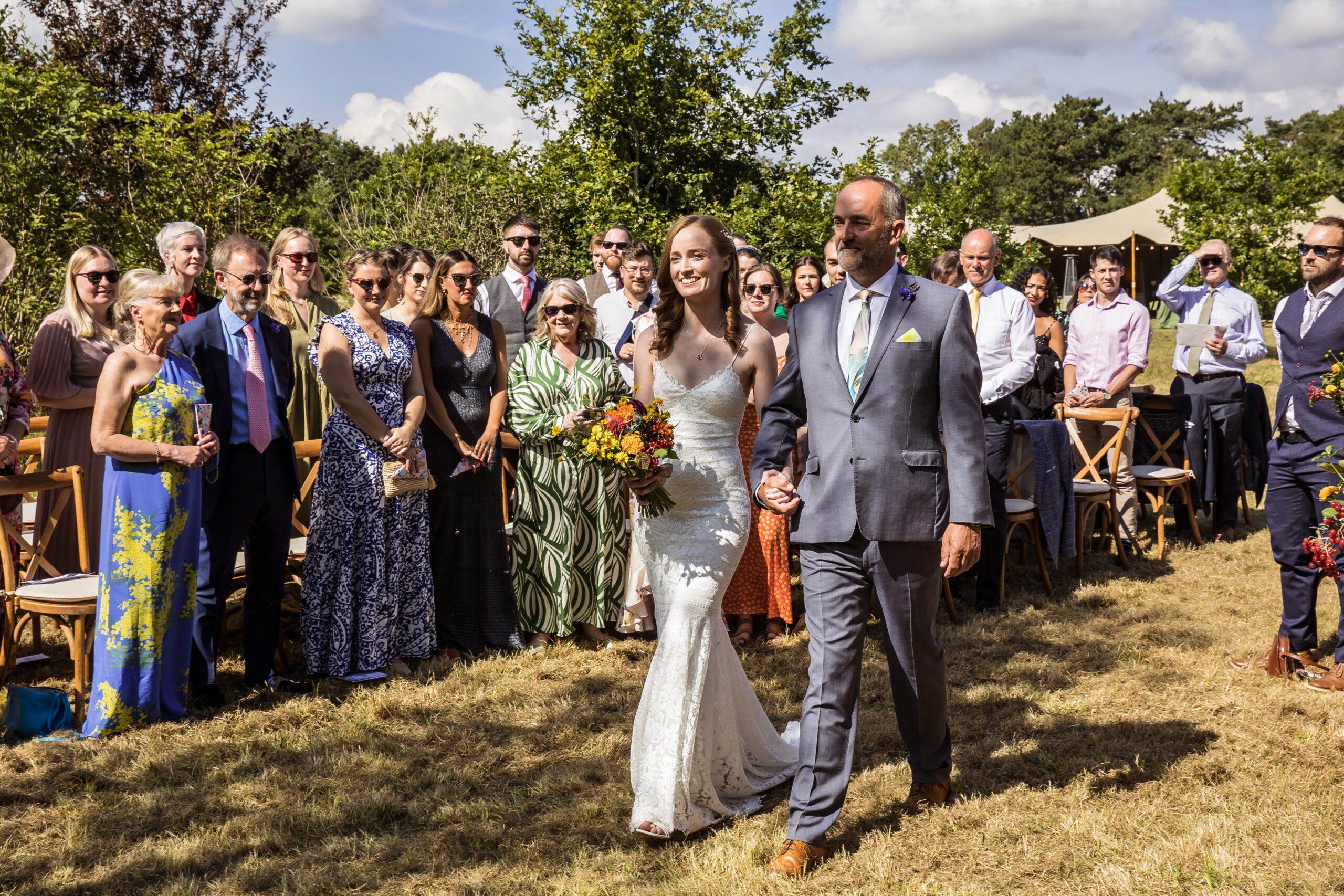 a bride and her father walk through a hertfordshire garden down the aisle