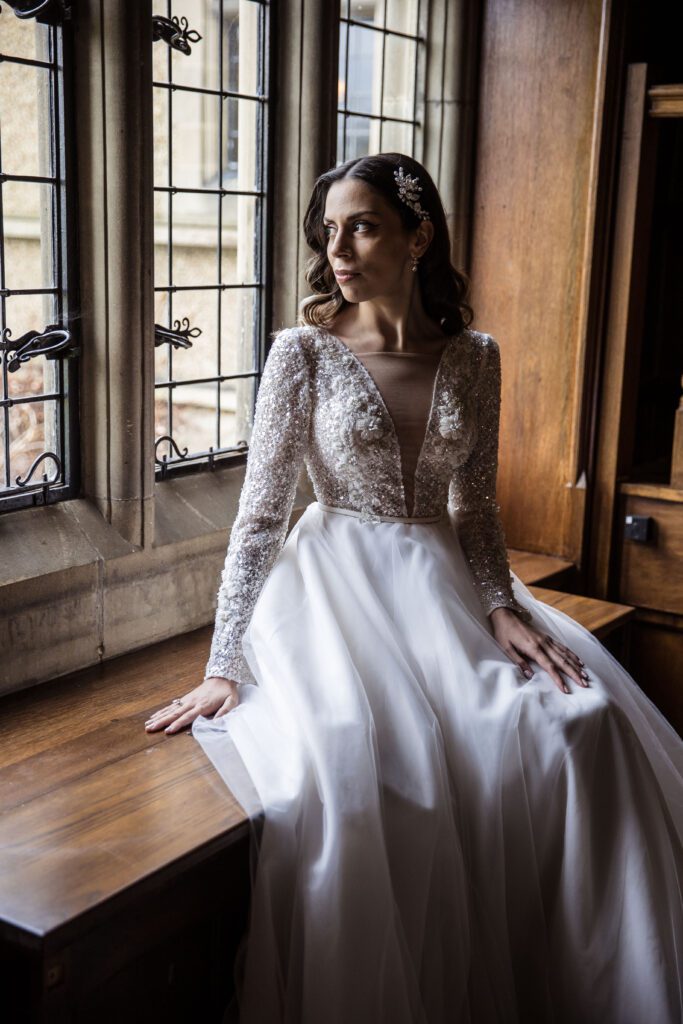 A bride looks out of a window just before her wedding at Fanhams Hall in Hertfordshire