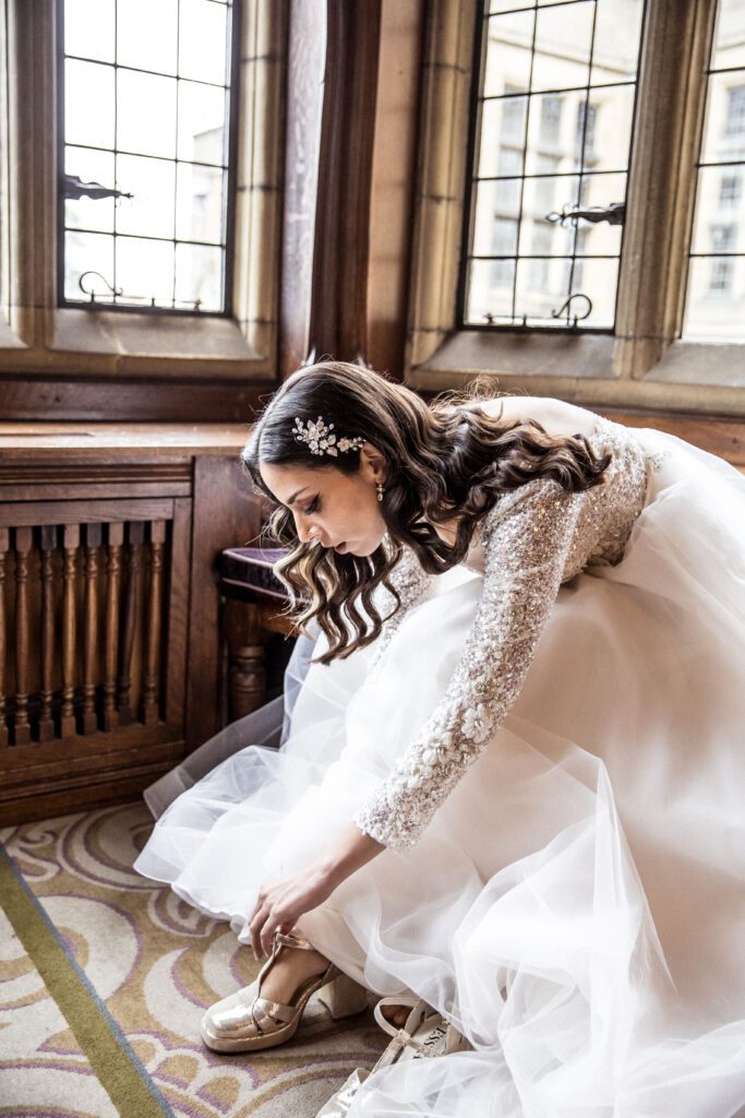 A bride buckles her shoe on the rooms of Fanhams Hall.