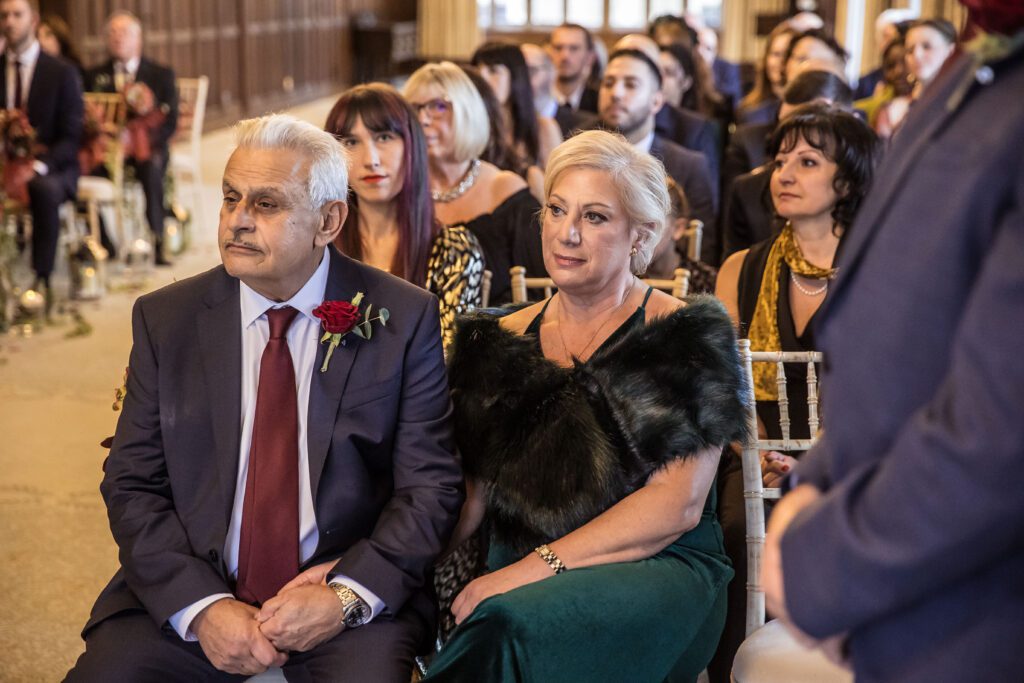 Mother and father of the bride watches as their daughter gets married at Fanhams Hall in Hertfordshire