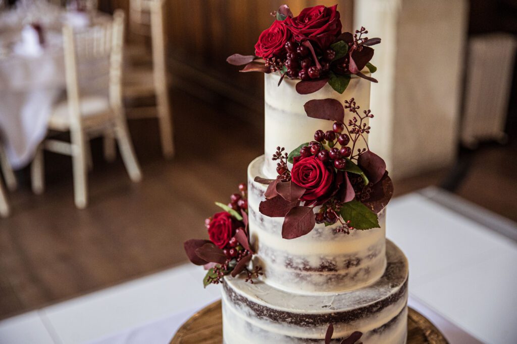 wedding cake decorated with autumn foliage and red roses at Fanhams Hall wedding