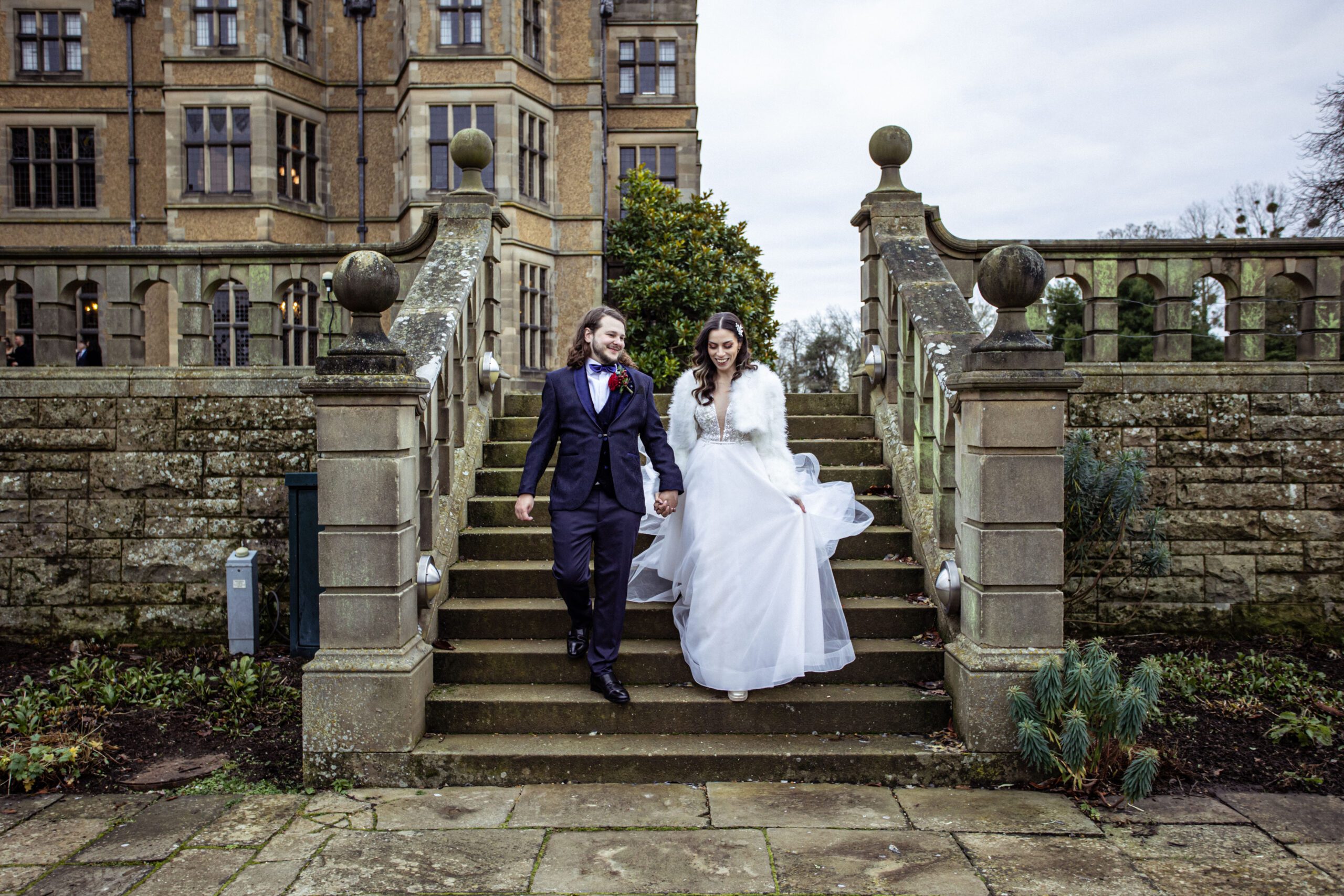 A bride and groom descends the steps in the gardens of Fanhams Hall after they say I do!