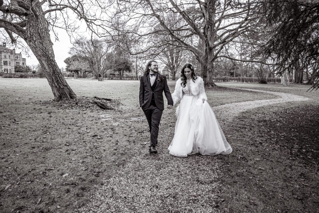 A bride and groom walk in the gardens of Fanhams Hall