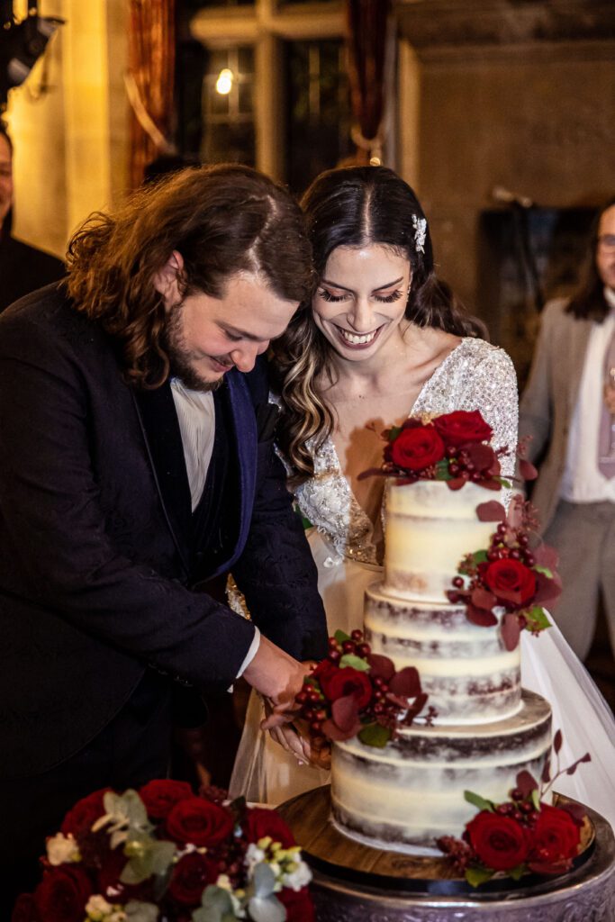 A bride and groom cut their cake at their wedding reception at Fanhams Hall.