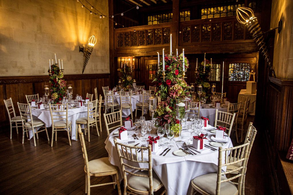 A table setting at a winter wedding at Fanhams Hall. A red rose flower display with candles sits on the table